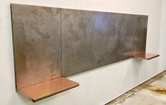 a wall mounted metal sculpture on the side of a white wall with wooden shelfs