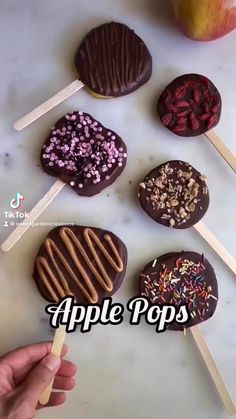 an apple pops with chocolate and sprinkles on it is being held by a hand