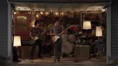 a group of people playing instruments in front of a garage with lights on the door