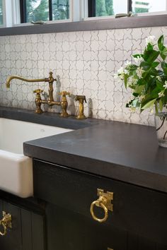 a vase with flowers in it sitting on a counter next to a sink and faucet