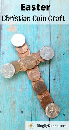 a cross made out of coins sitting on top of a blue wooden floor with one coin in the middle