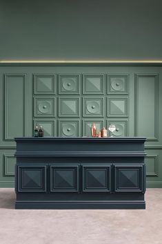 an empty bar with bottles and glasses on it in front of green wallpapered walls