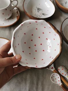 someone is holding a bowl with hearts on it and spoons in front of them