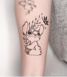 a small tattoo on the arm of a girl with a cute cartoon character holding a leaf