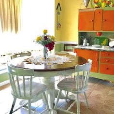 a dining room table with white chairs and yellow walls