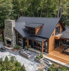 an aerial view of a house in the woods with wood and stone accents on the roof