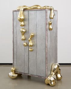 a large wooden box with gold handles and feet on the floor next to some shoes