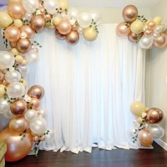 the balloon arch is decorated with gold, white and pink balloons in front of a window