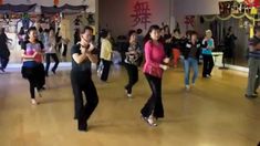 a group of people are dancing in a dance hall with chinese characters on the walls