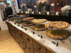 several pizzas are on display in front of candles and vases filled with flowers