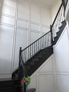 a black and white staircase in a house with wall panels on the walls behind it