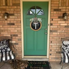 two lawn chairs sitting in front of a green door with a welcome mat on it