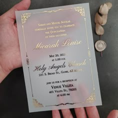 a person holding up a white and gold wedding card