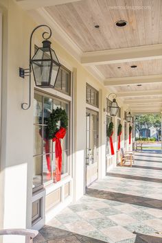 the front porch is decorated for christmas with red bows and wreaths hanging from the windows