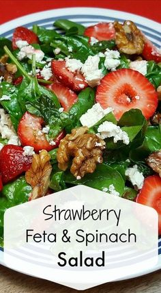 a salad with strawberries, feta and spinach on it in a blue and white plate