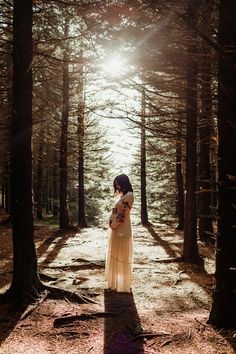 a woman standing in the middle of a forest with her hands on her chest and looking up