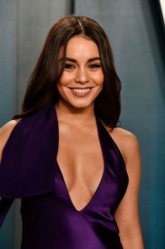 a woman in a purple dress smiling at the camera