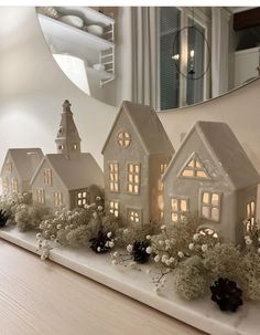 a group of small white houses sitting on top of a table next to a mirror