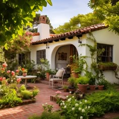 a white house with lots of plants and flowers around it's front entrance area