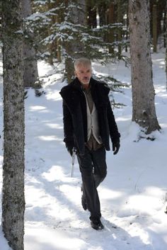 an older man walking through the snow with skis