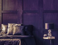 a bedroom with purple walls and gold bedding