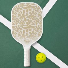 a tennis racket and ball on a green surface with white lines in the background