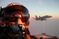 two fighter jets flying in the sky next to each other with one pilot wearing goggles