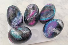 five marbled eggs sitting on top of a white tray covered in purple and blue paint