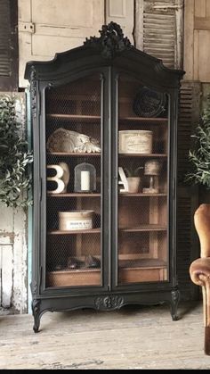 an old fashioned china cabinet with glass doors and leather chair in front of the hutch