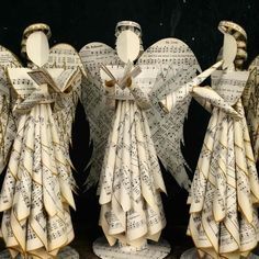 three angels made out of sheet music are standing next to each other with their wings folded over them