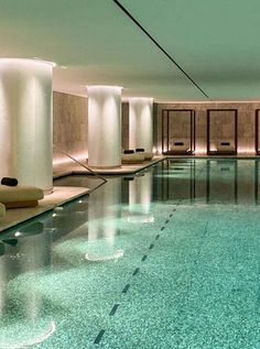 an indoor swimming pool surrounded by columns and lights at the end of each column is lit up with candles