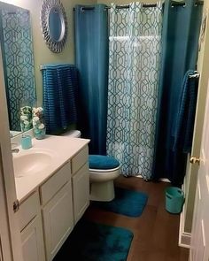 a bathroom with blue shower curtains and rugs on the floor in front of the sink