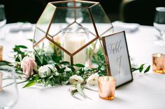 the table is set with candles, flowers and greenery for an elegant wedding reception