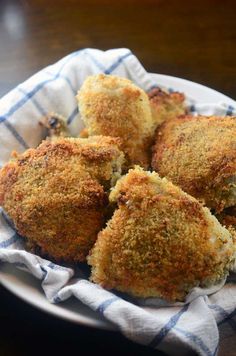 four pieces of fried food on a white plate with a blue and white checkered napkin