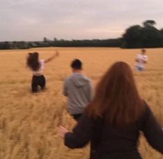 three people are running through a field with one person in the foreground holding out their arms