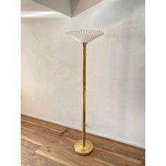 a gold floor lamp in the corner of a room with white walls and wood floors