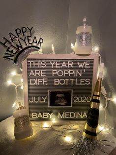 a sign that says happy new year and two champagne bottles next to it on top of a table