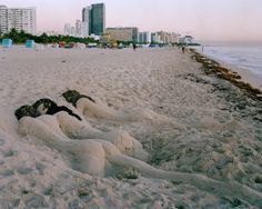 the sand is covered with white foam and has buildings in the background