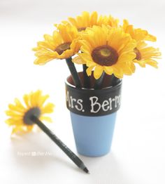 two yellow flowers in a blue vase with writing on it