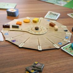 a board game on a wooden table with dices and token cards scattered around it