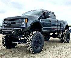 a large black truck parked on top of a sandy beach