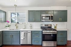 a kitchen with blue cabinets and stainless steel appliances, including an oven, dishwasher, sink, microwave, and stove