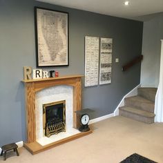 a living room with a fire place next to a stair case and pictures on the wall