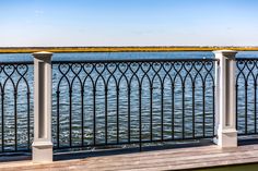 an iron fence overlooking the ocean on a sunny day with blue sky and water in the background