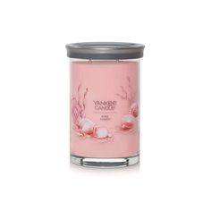 yankee candle with pink flowers and leaves on the front, in a glass container against a white background