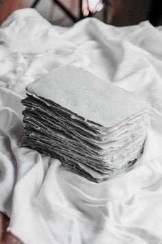 a stack of folded papers sitting on top of a bed