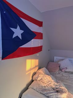 an american flag hanging over a bed in a room with white walls and flooring