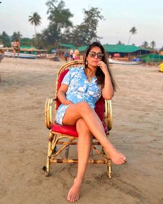 a woman sitting in a chair on the beach with her feet up to her face