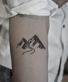 a person with a tattoo on their arm that has two mountains in the middle of it