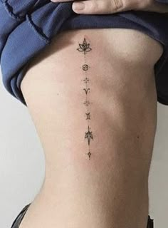 a woman's lower back tattoo with symbols on her left side ribcage